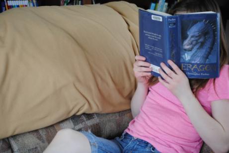 Ein Kind ein Mädchen liest ein Buch auf dem Sofa.